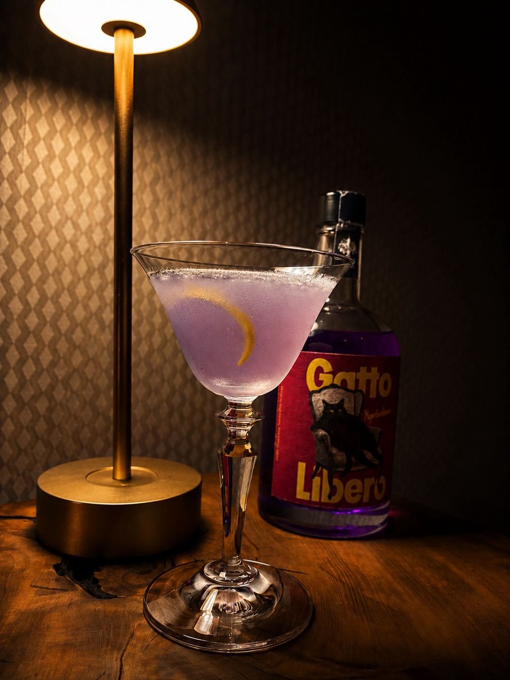 A pale violet gin cocktail with a lemon twist