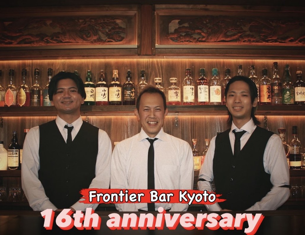 Bartenders Jun, Toshi and Kain smiling behind the bar, celebrating Frontier Bar Kyoto's 16th anniversary